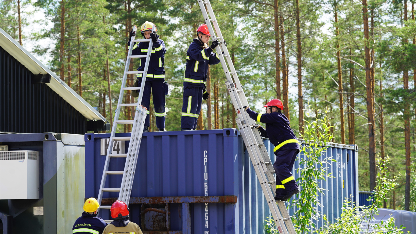 Palokuntanuoret harjoittelevat tikkailla kiipeämistä kontin päälle.